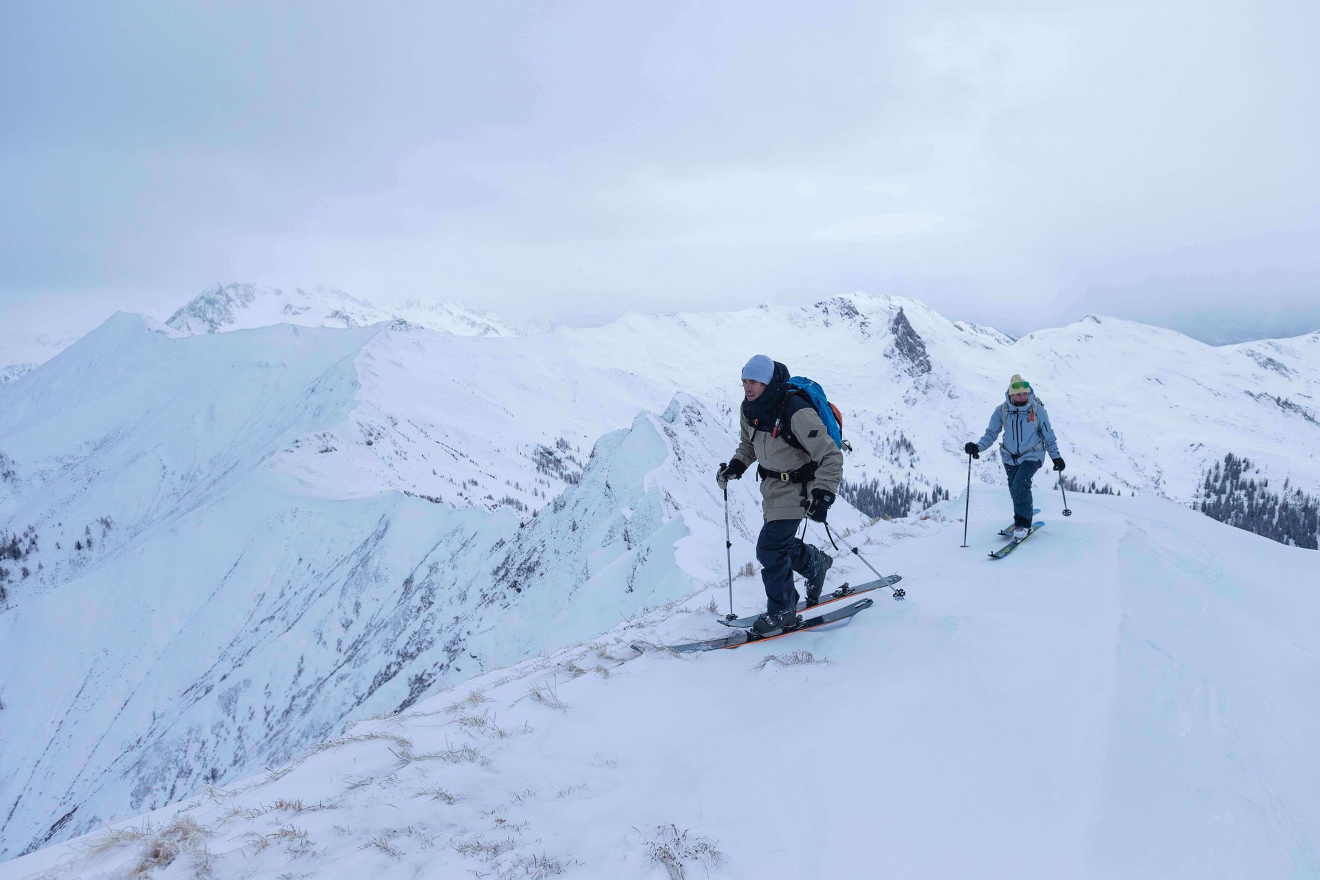 Das Bild zeigt zwei Personen, die in den Bergen eine Ski Touring Tour unternehmen.
