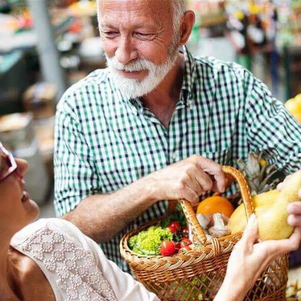 Auf dem Bild stehen ein Mann und eine Frau an einem Oststand am Markt. Sie wollen mit gesunder Ernährung gegen ihre Arthrose ankämpfen.
