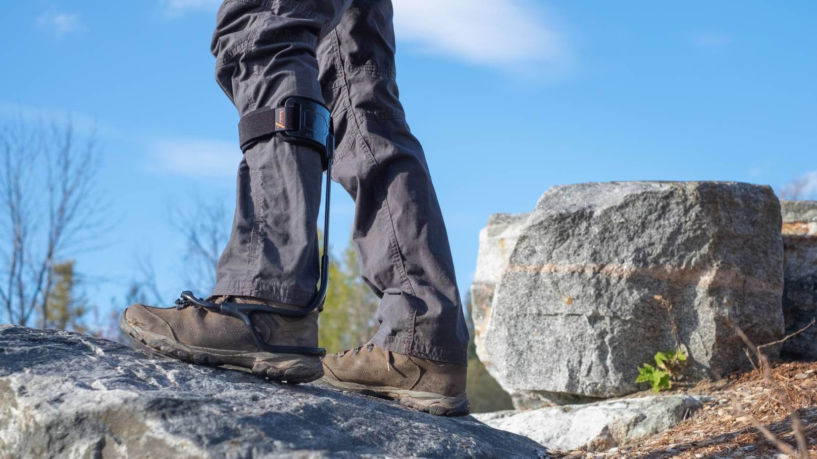 Person beim Wandern auf Felsen mit einer Fußheberorthese am rechten Bein zur Unterstützung bei Fußheberschwäche.