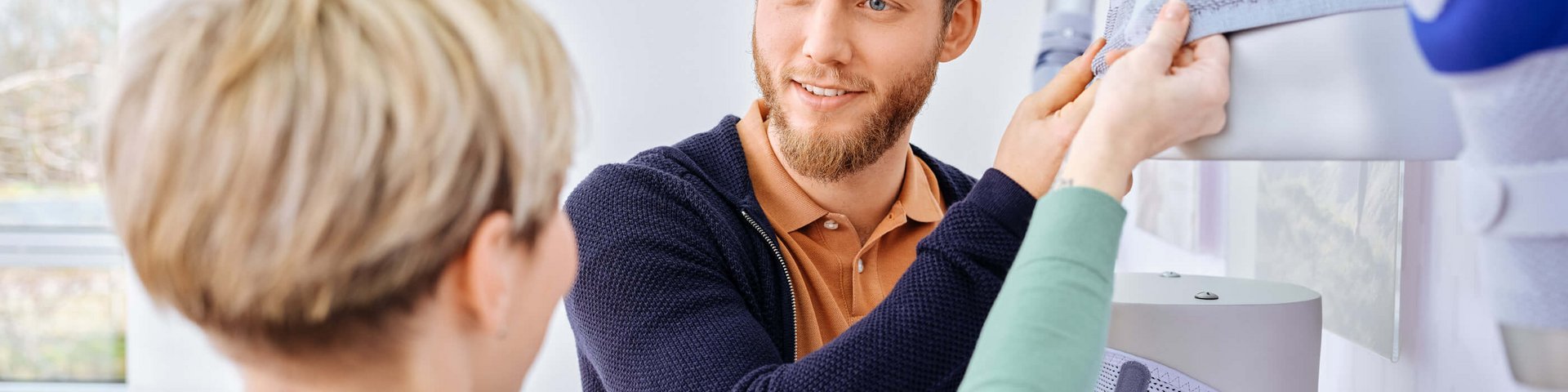 Ein Berater zeigt einer interessierten Patientin die Rückenbandagen von Bauerfeind in einem Showroom.