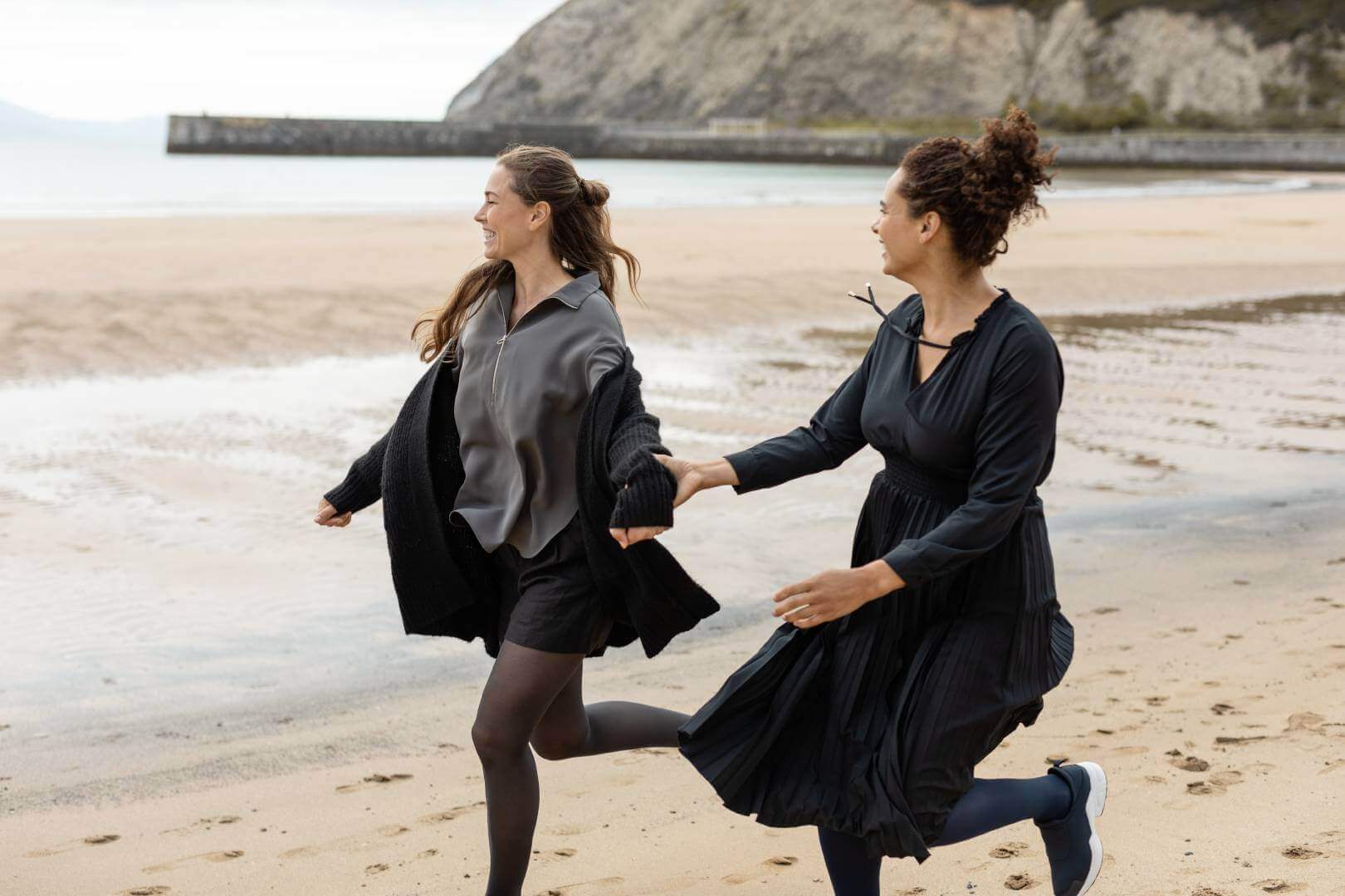 Zwei Frauen laufen am Strand. Beide tragen VenoTrain micro Kompressionsstrümpfe von Bauerfeind.