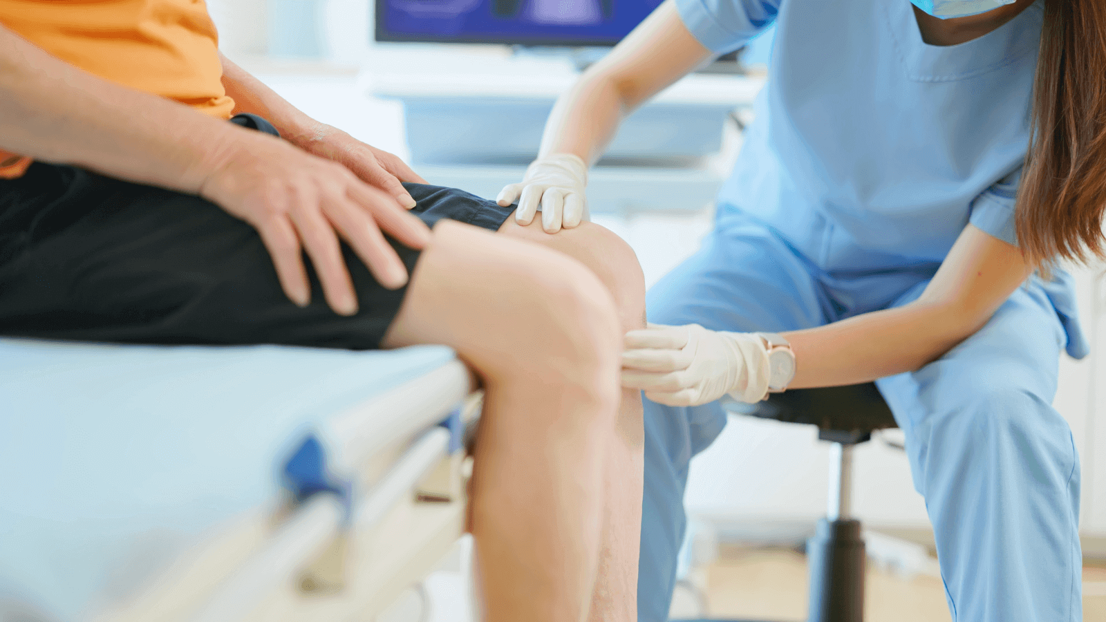 Das Bild zeigt eine Ärztin, die das Knie eines Patienten untersucht.